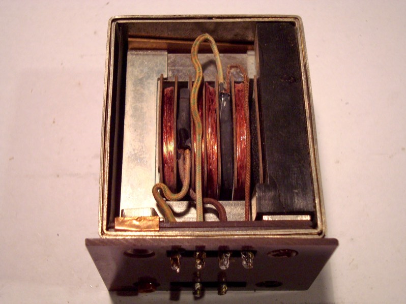 Laminations isolated from screening can by cardboard layers & inner bakelite foot. Outer bakelite foot isolates from chassis. Top left screw hole provides only contact to laminations (via washer) & screening can (via copper foil). Other screws go through plastic tubing & rest in plastic "L" spacers (right) for complete isolation. Note double layers of mu metal screen, with copper foil inbetween